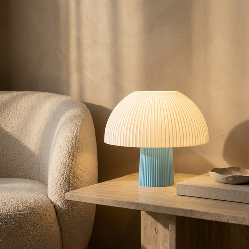 Ribbed mushroom table lamp glowing on a travertine side table in golden-hour light